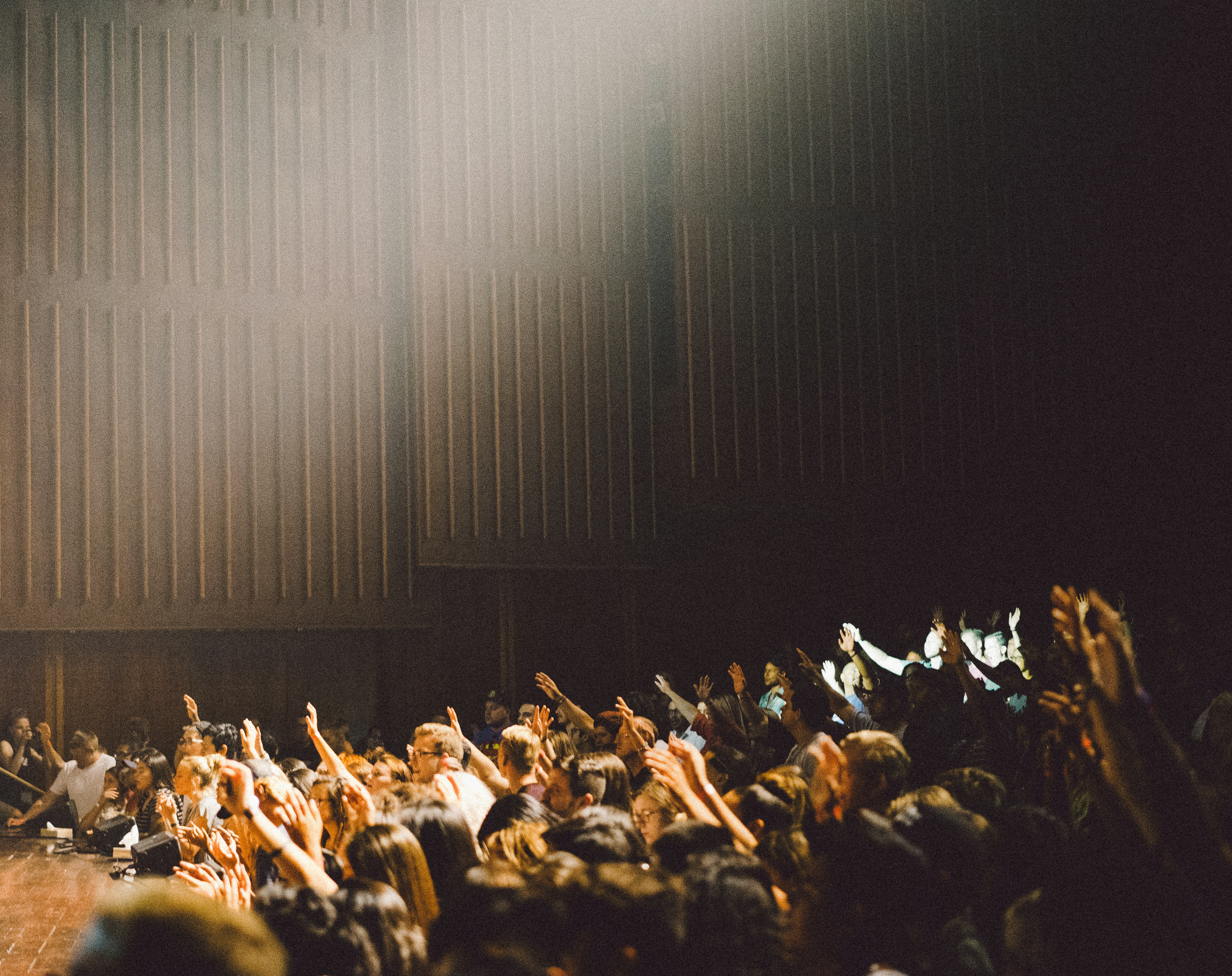 A lecture hall filled, with many student leaning forward and raising hands.